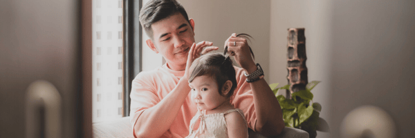 Father tying daughter's hair into a pony tail
