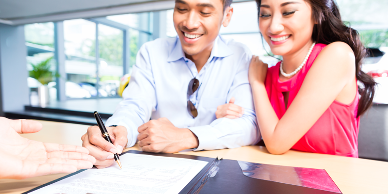 Young Couple Signing Contract at Car Dealership