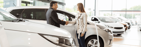 Man and woman shaking hands in car dealership