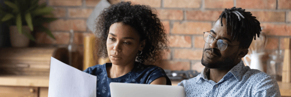 One person holding papers and one person on a laptop