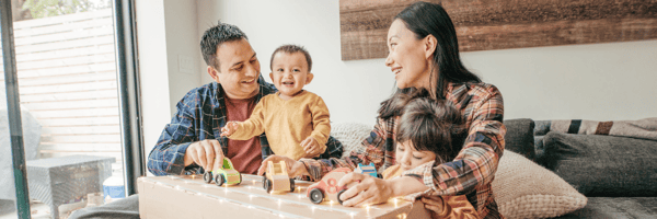 mother and father playing toy cars with their two young boys.