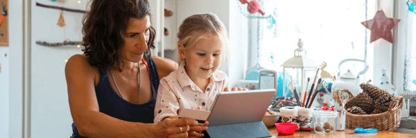 Mom and daughter shopping online at home using a gift card.