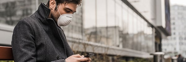 Man looking at account information on phone with surgical mask on.