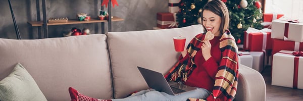 Woman online holiday shopping from her couch.