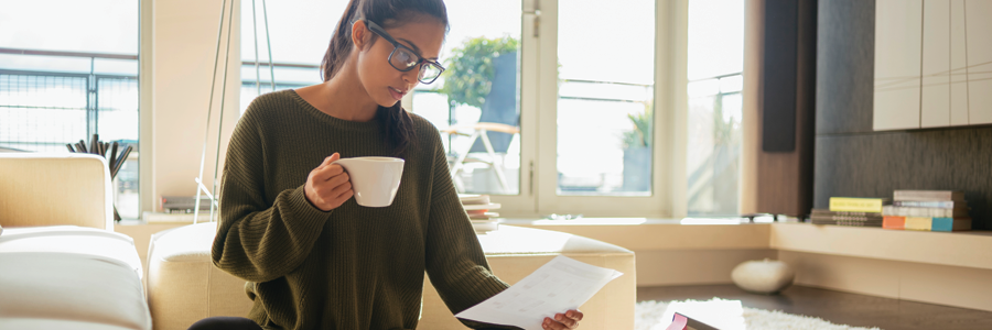 Woman reading paper work on couch.