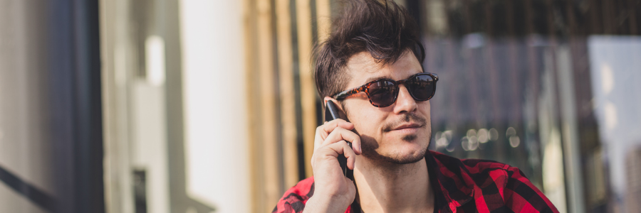Man wearing sunglasses and talking on the phone. 