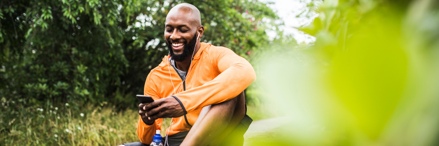 Man resting during a workout by looking at phone and smiling.