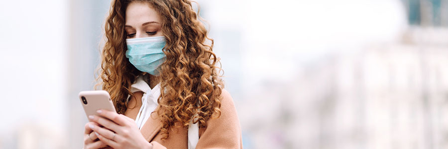 Woman wearing a face mask and looking at her phone. 